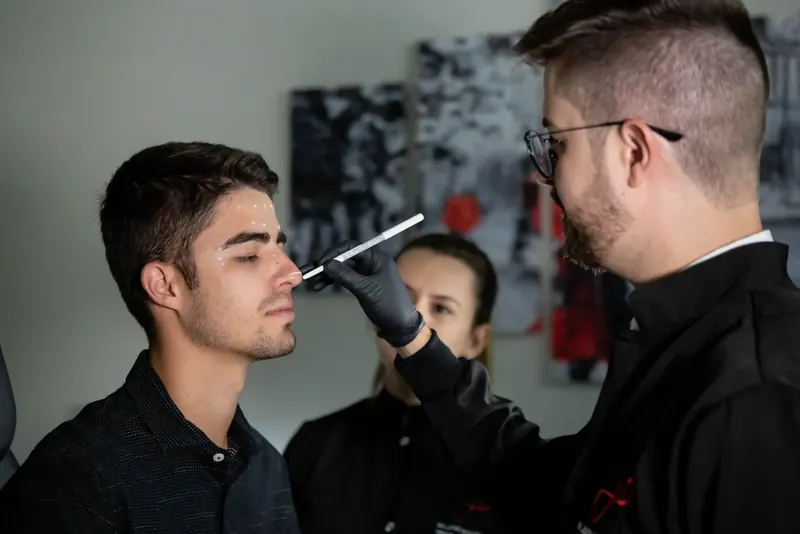 Assessment where the doctor makes markings on the patient's face during a rhinoplasty examination